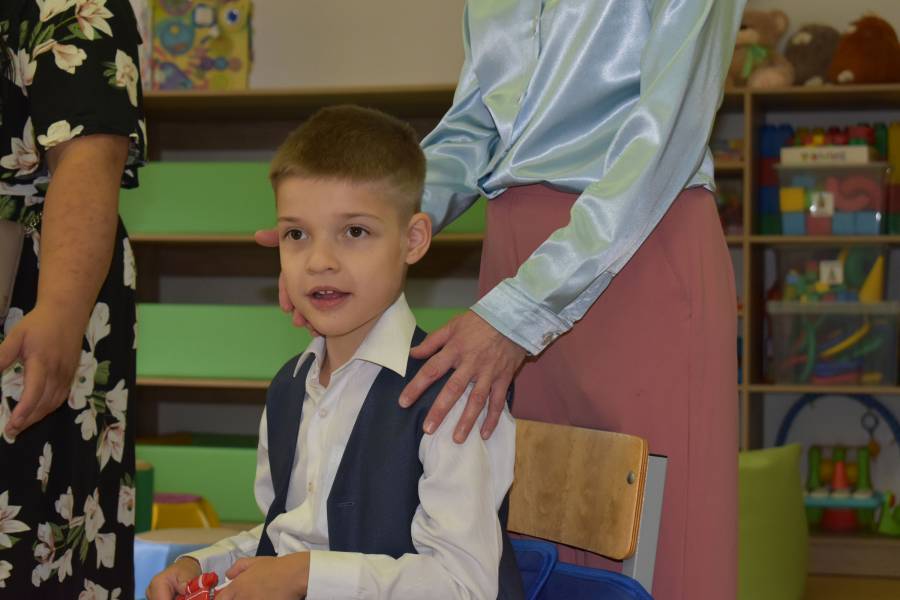 Der kleine Artur im Klassenzimmer, seine Mutter legt im die Hand auf die Schulter