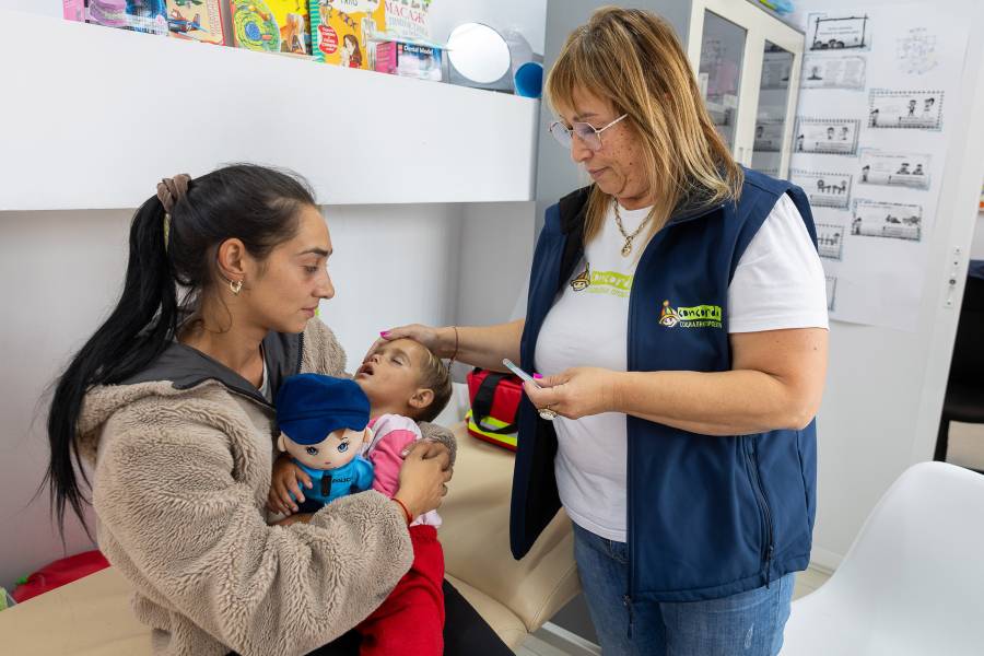 Eine junge Frau mit ihrem kranken Kleinkind wird in der Krankensprechstunde im Concordia-Zentrum in Malki Iskar von einer Mitarbeiterin betreut.