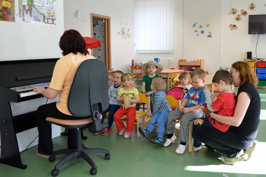 Kinder singen zusammen mit ihrer Betreuerin